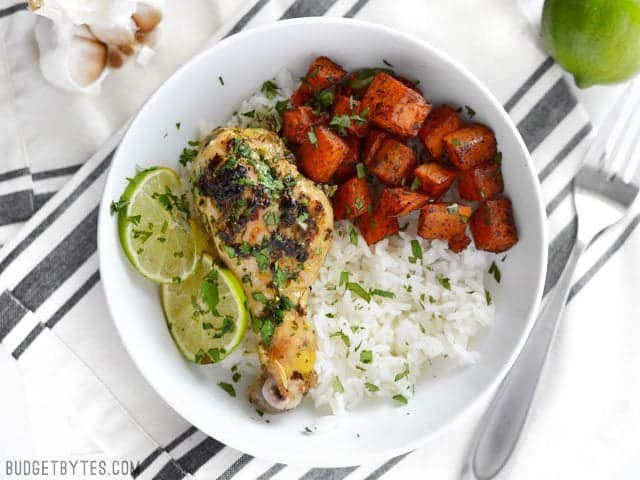 Overhead view of a bowl with Cilantro Lime Chicken Drumsticks and chili roasted sweet potatoes over rice