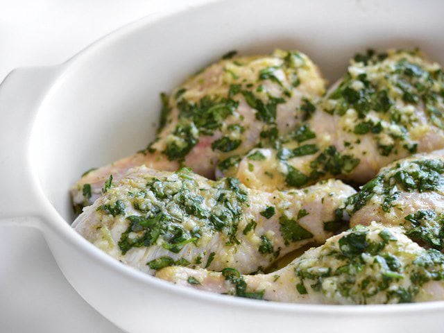 Close up side view of uncooked chicken in the baking dish, remaining marinade poured over top