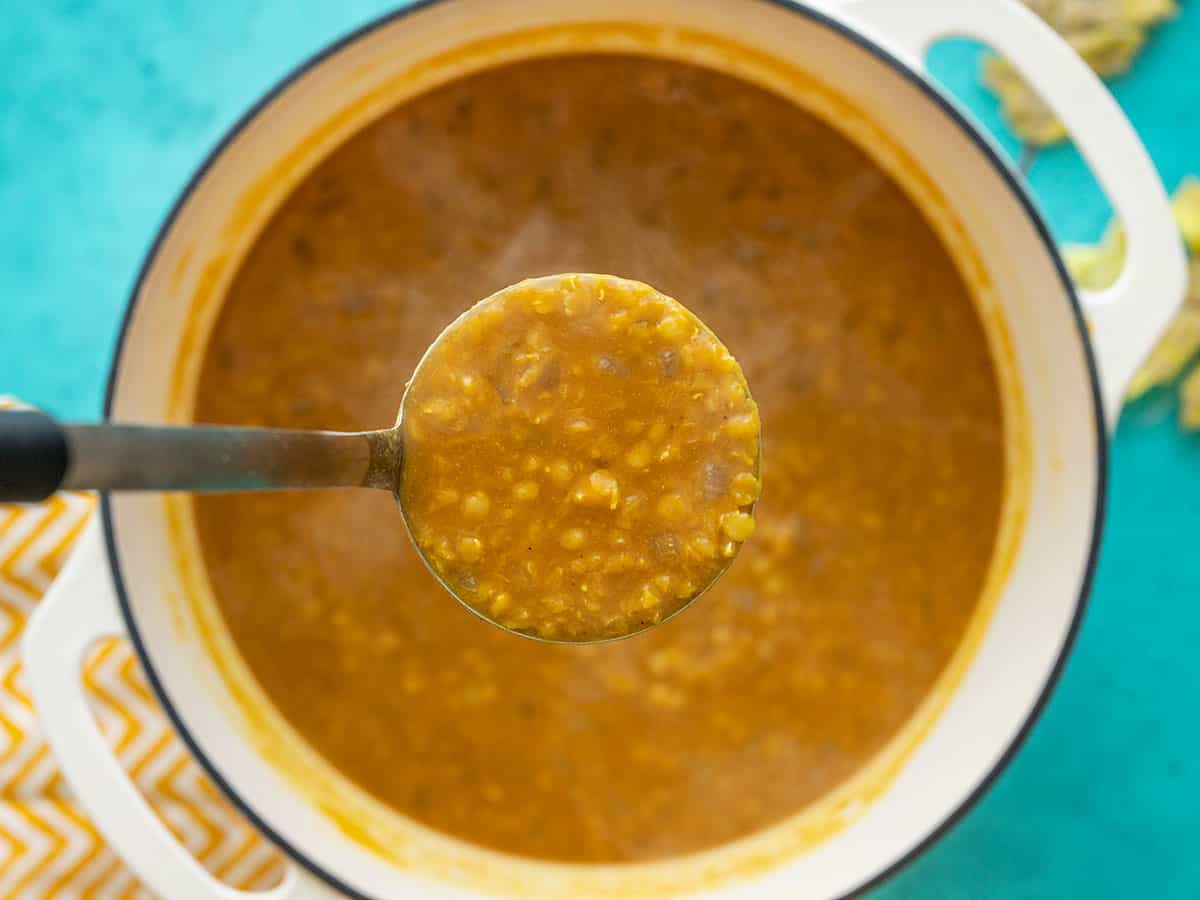 close up of a ladle full of lentil and pumpkin soup