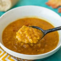 A spoonful of lentil and pumpkin soup being lifted from the bowl