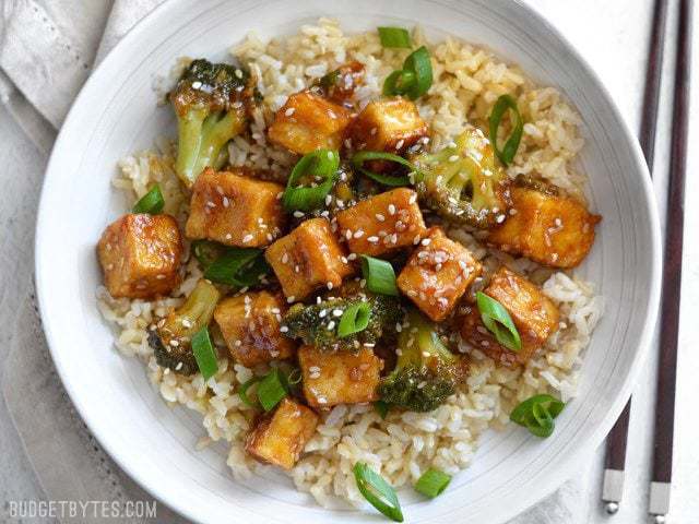 Finished pan fried sesame tofu with broccoli and brown rice in a white bowl