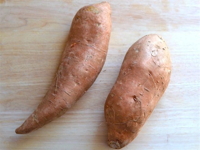 Sweet Potatoes whole on a wooden cutting board