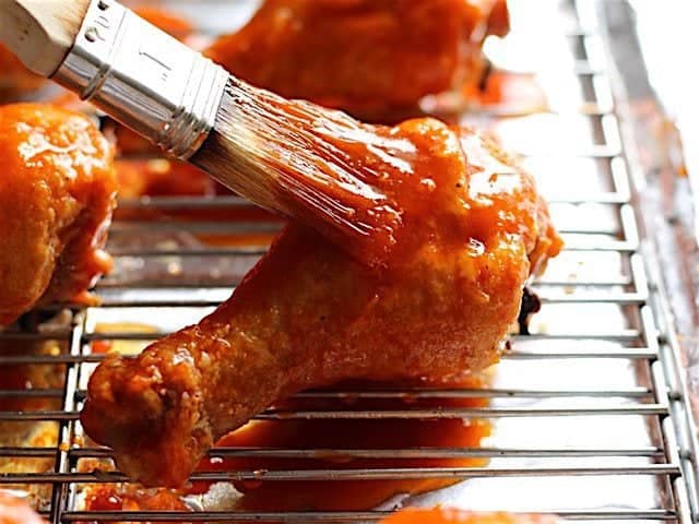Honey Sriracha sauce being brushed over the chicken drumsticks