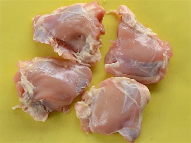 Four Chicken Thighs, Skin Removed, on a yellow cutting board