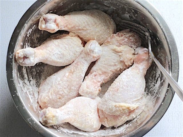 Raw chicken drumsticks coated in cornstarch