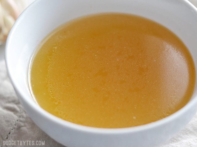 Close up side view of a bowl full of golden chicken stock