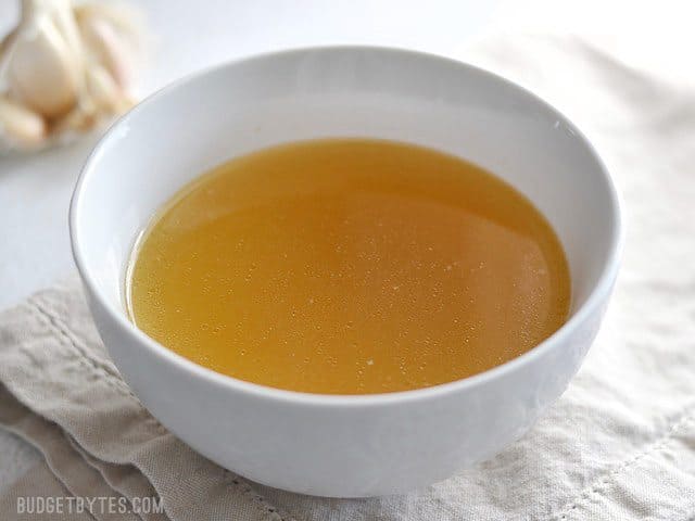 Side view of a bowl full of rich, golden chicken stock made in an Instant Pot