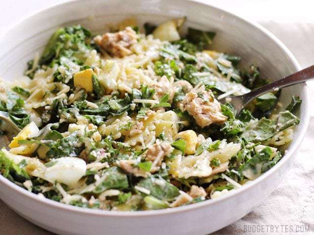 Kale & Salmon Caesar Salad in a white bowl with a fork 