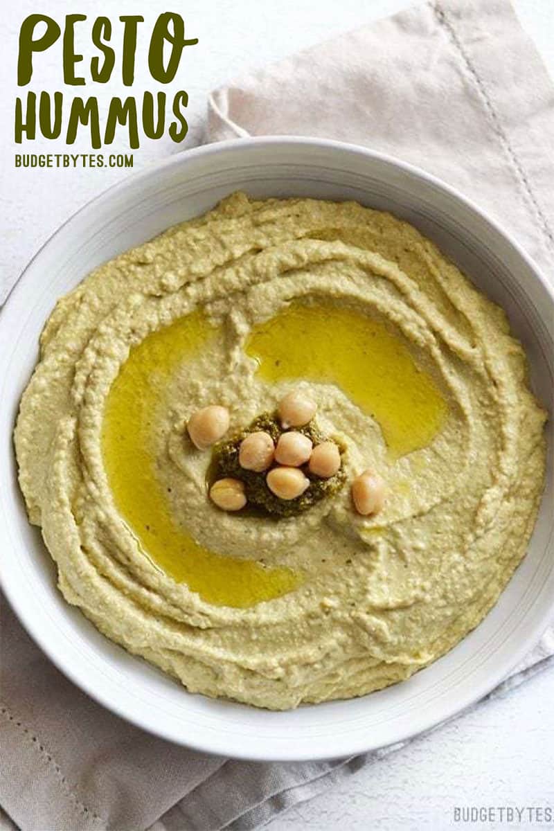 Overhead view of a bowl of pesto hummus, title text in the top corner