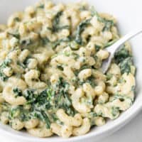 Close up side view of a bowl of creamy pesto mac with spinach