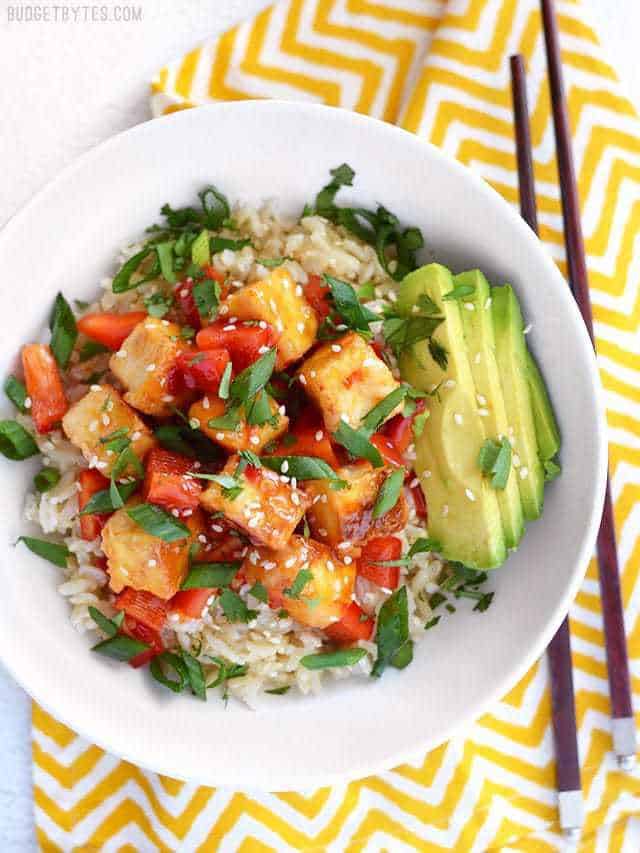 Overhead view of a Sweet Chili Tofu Bowl on a yellow zig zag napkin, chopsticks on the side