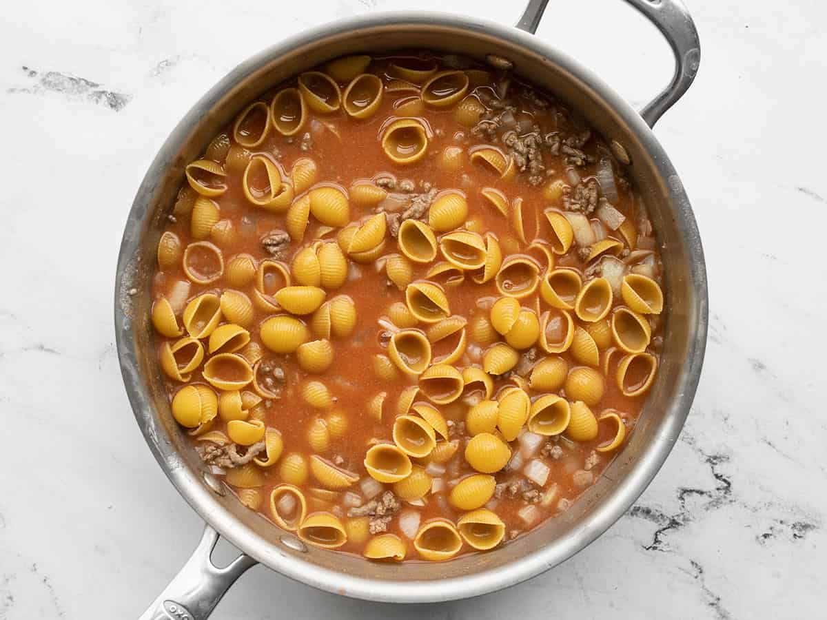 Uncooked pasta shells added to the skillet