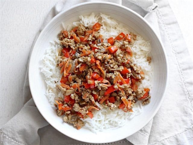 Stir fried pork and vegetables spooned over a bowl of rice