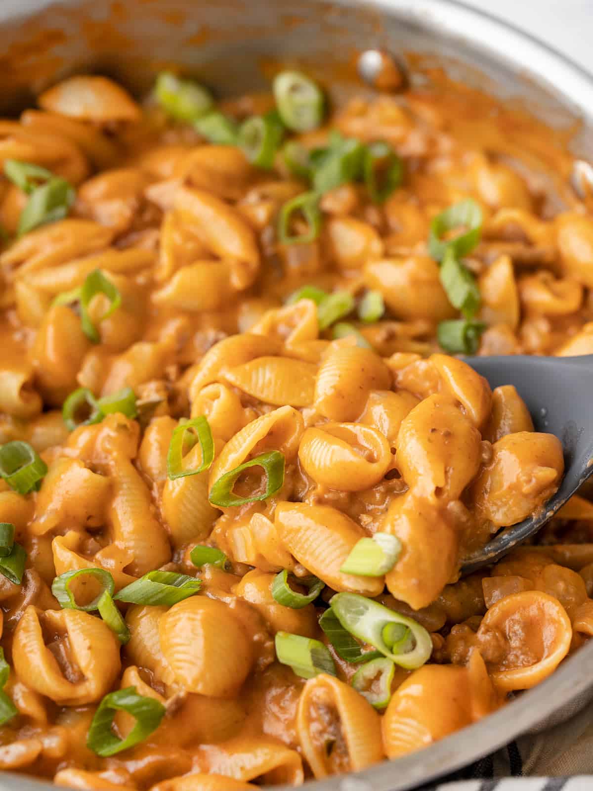 Close up side view of cheeseburger pasta skillet with a spoon dug in the side