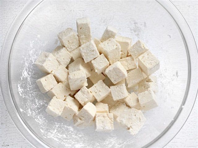 Cubed Tofu coated in cornstarch in a glass bowl