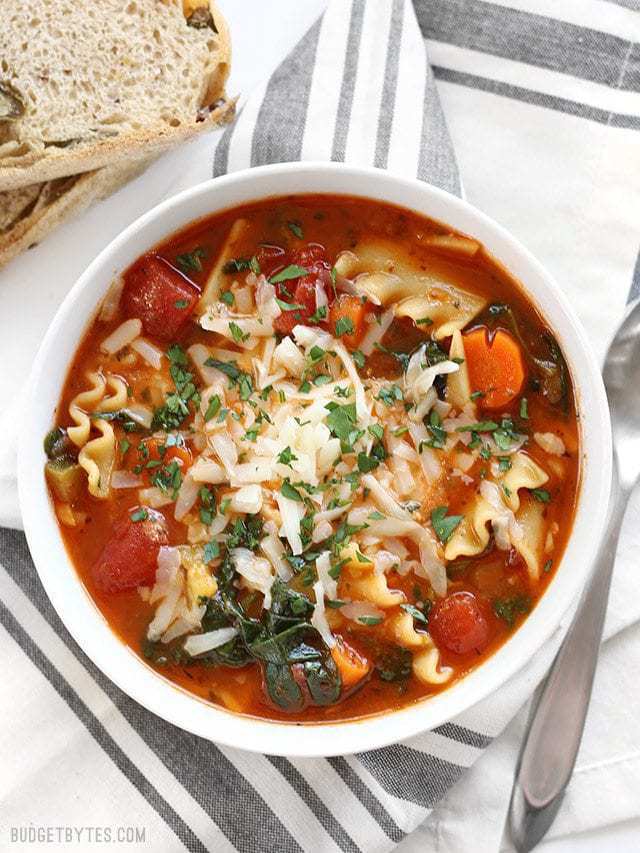 This Garden Vegetable Lasagna Soup is packed full of vegetables and lasagna flavor, plus a hidden dollop of melty three cheese ricotta blend in the middle! BudgetBytes.com Overhead view of a bowl full of Garden Vegetable Lasagna Soup with crusty bread on the side