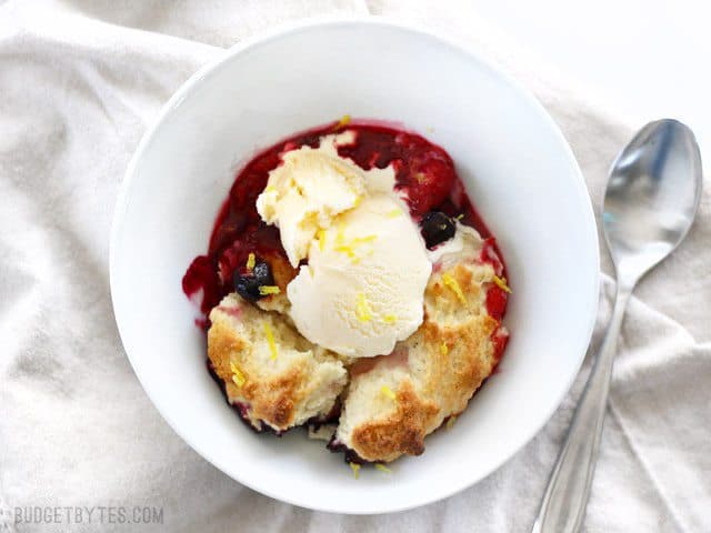 Overhead view of a bowl of Lemon Berry Cobbler topped with vanilla ice cream