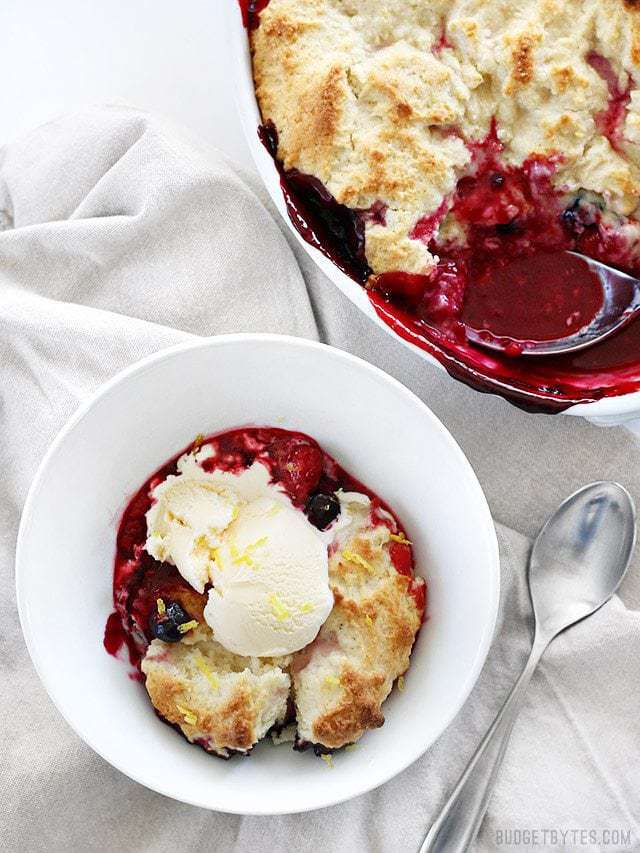 Overhead view of a Lemon Berry Cobbler next to a bowl that has been served and topped with ice cream