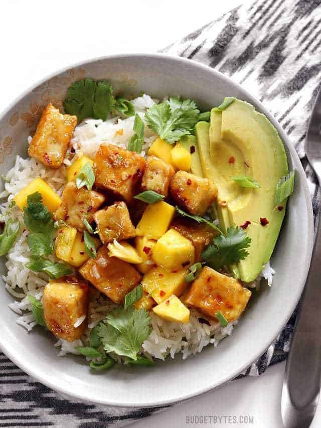 Close up overhead view of a Mango Coconut Tofu Bowl sitting on a stripped napkin.