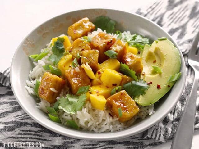 Front view of a Mango Coconut Tofu Bowl with red pepper flakes sprinkled over top