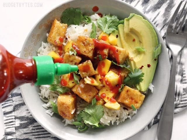 Sriracha being drizzled on a Mango Coconut Tofu Bowl