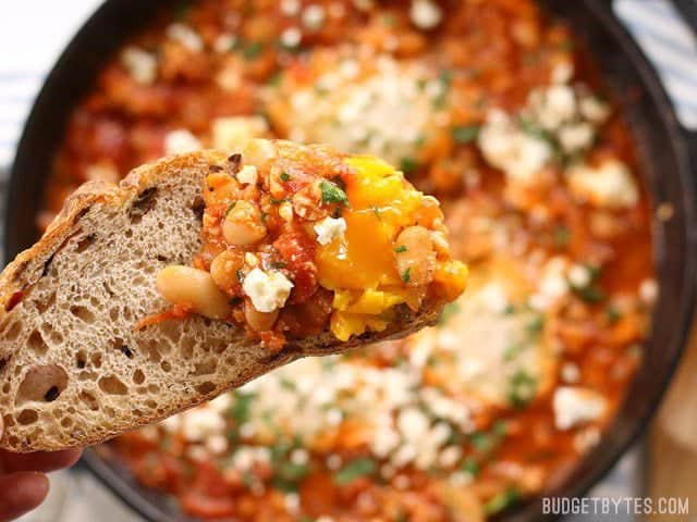 Close up of a slice of bread with some Smoky White Bean Shakshuka on the end.