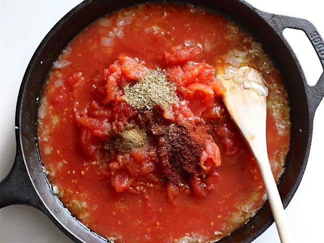 Tomatoes and spices added to the skillet with onion and garlic