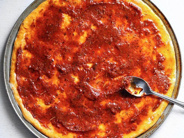 Tomato sauce spread on pizza dough