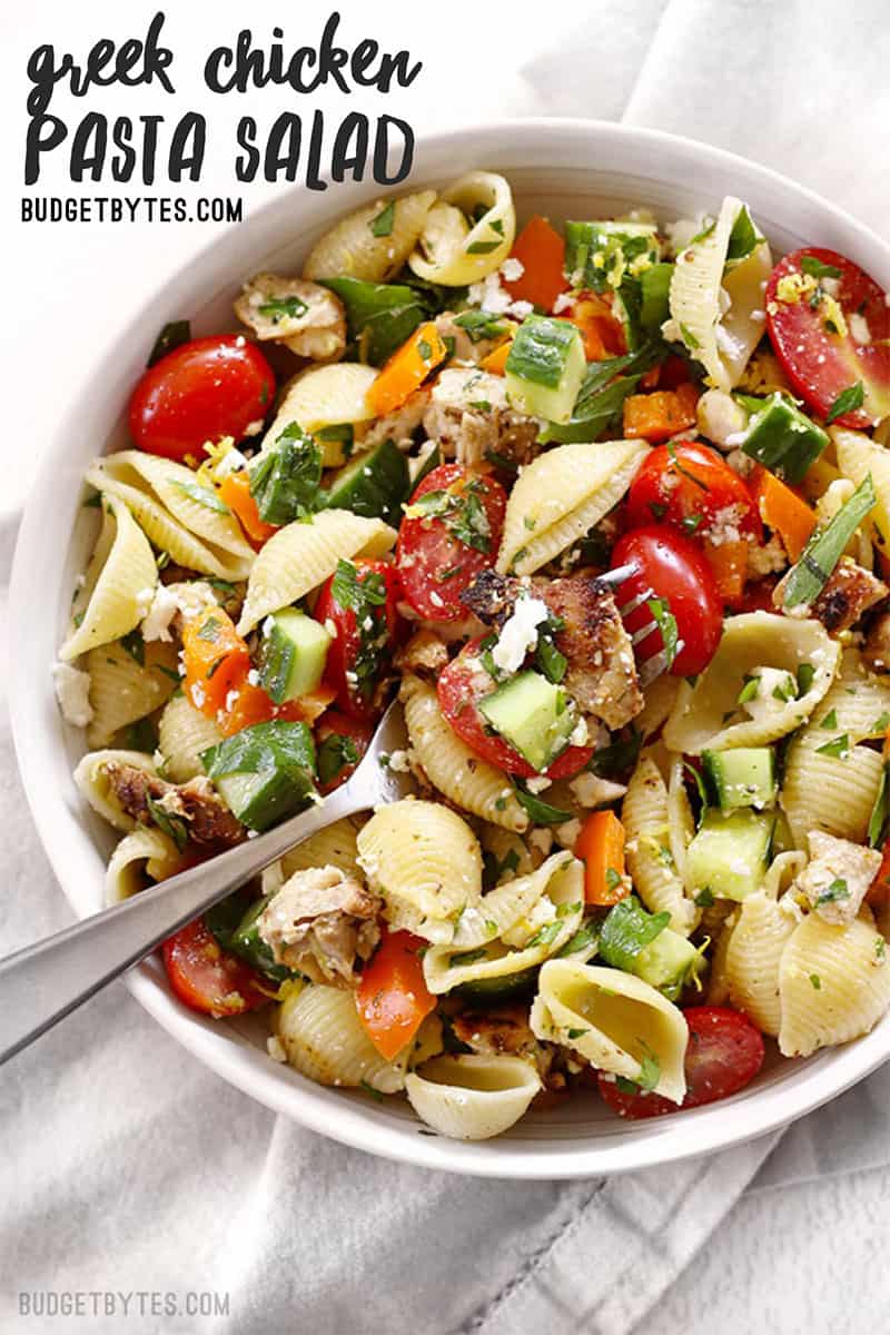 Close up overhead view of a bowl full of Greek Chicken Pasta Salad with title text in top corner.