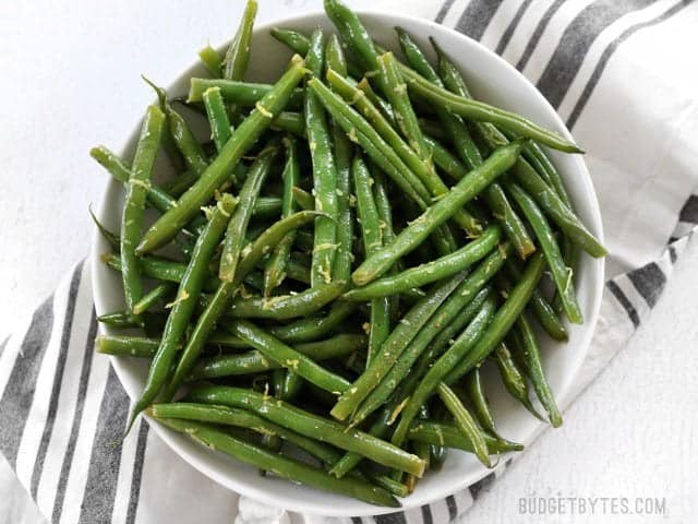 A large bowl full of Lemon Butter Green Beans garnished with lemon zest, viewed from above