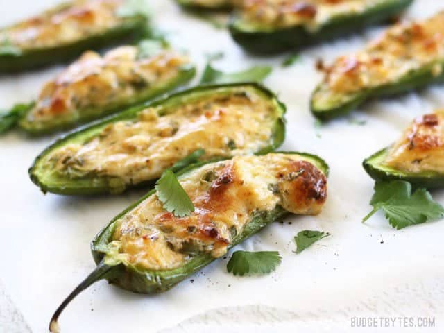 Side view of baked cheesy scallion stuffed jalapenños, close up.