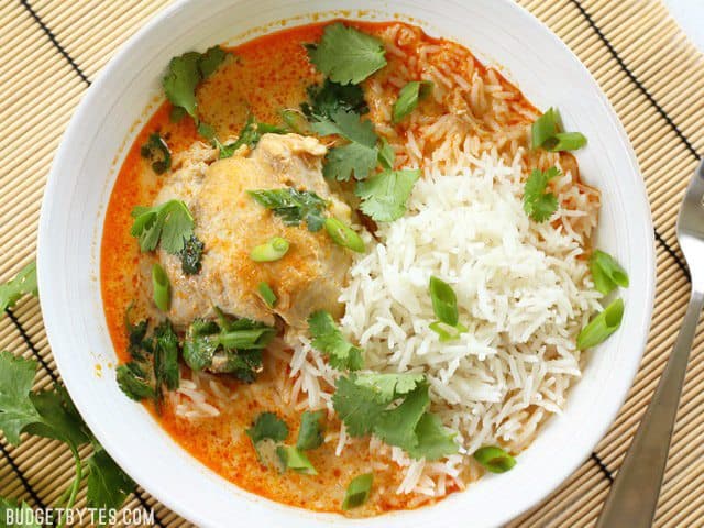 A bowl of Thai Coconut Curry Braised Chicken Thighs served with jasmine rice and cilantro