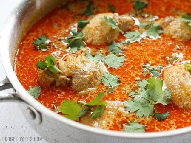 Side view of the Thai Coconut Curry Braised Chicken Thighs in the skillet, garnished with cilantro