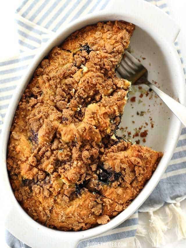 Overhead view of casserole dish with Blueberry Buttermilk Coffee Cake, a few pieces cut out and a fork resting in their place.