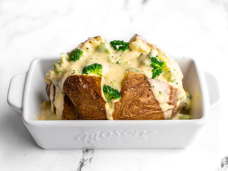 Side view of a baked potato with broccoli cheese sauce