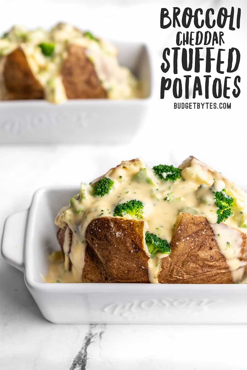 Two baked potatoes with broccoli cheese sauce in white ceramic dishes