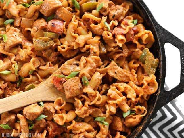 Close up overhead view of Creamy Chicken Fajita Pasta in the skillet with a wooden spoon