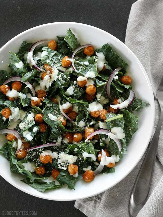 Overhead view of a Kale Salad with Cajun Spiced Chickpeas in a white bowl on a black background