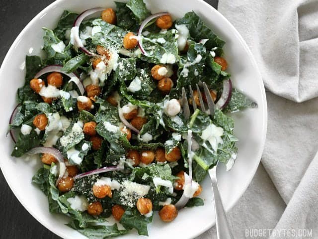 Overhead view of Kale Salad with Cajun Spiced Chickpeas and Buttermilk Dressing on a black background
