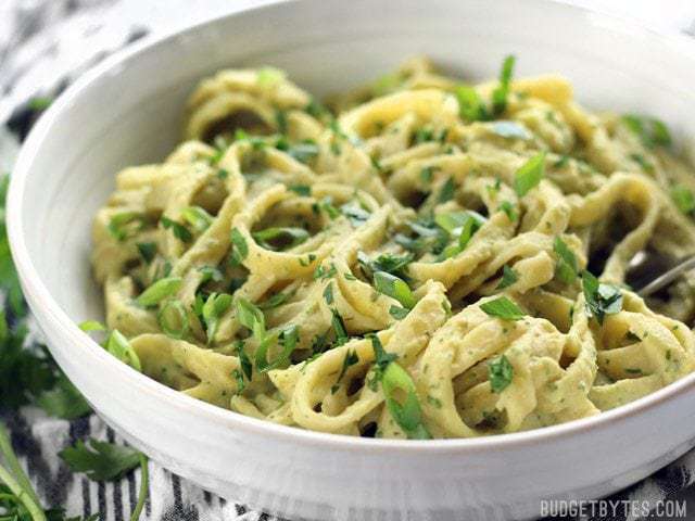 Close up side view of a bowl of Parsley Scallion Hummus Pasta garnished with fresh chopped parsley