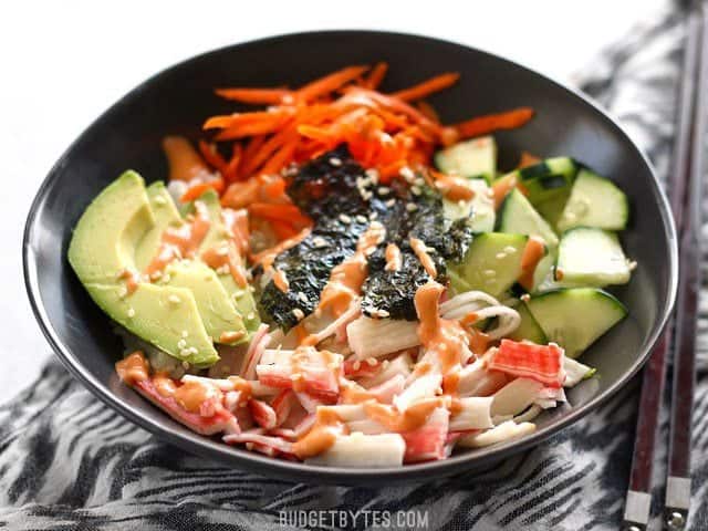 Front view of a homemade sushi bowls garnished with sriracha mayo and sesame seeds