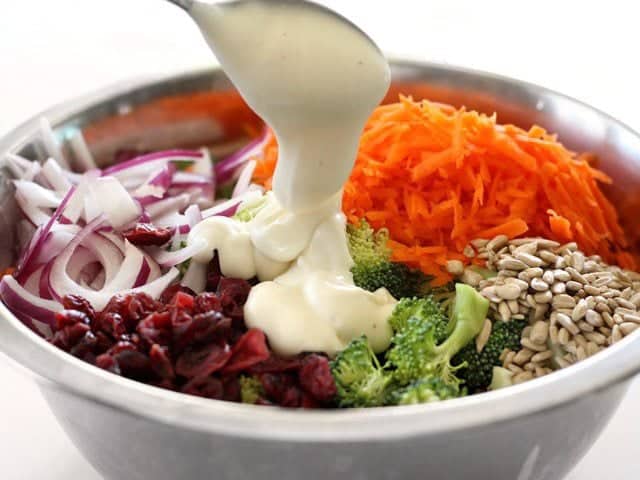 Honey yogurt dressing being added to the ingredients in the metal mixing bowl