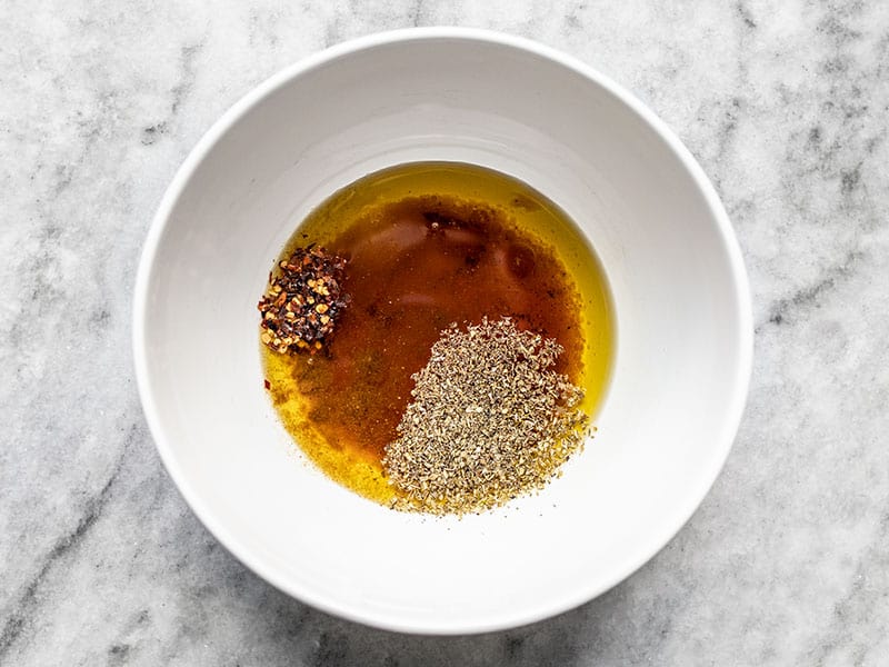 Red wine vinegar, olive oil, cumin, oregano, and red pepper in a bowl