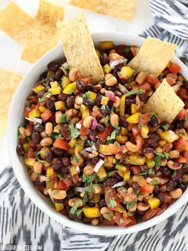 A large bowl of Cowboy Caviar with tortilla chips dipping into the salad. 