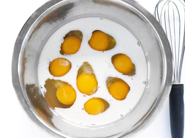 Milk Eggs Salt and Pepper in a bowl with a whisk on the side