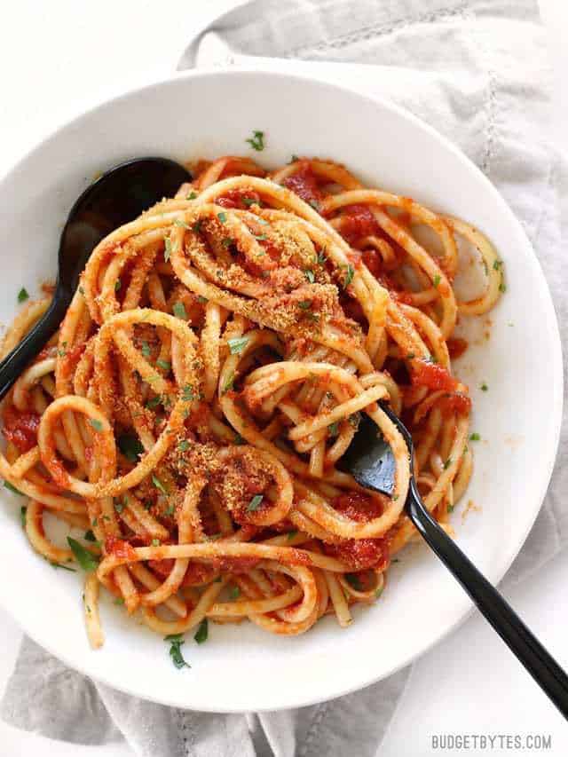 Overhead view of Pasta with 5 Ingredient Butter Tomato Sauce and toasted breadcrumbs in a bowl with a black spoon and a black fork
