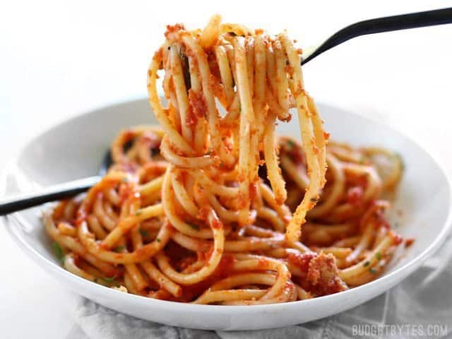 A forkful of Pasta with 5 Ingredient Butter Tomato Sauce being lifted out of the bowl, side view.