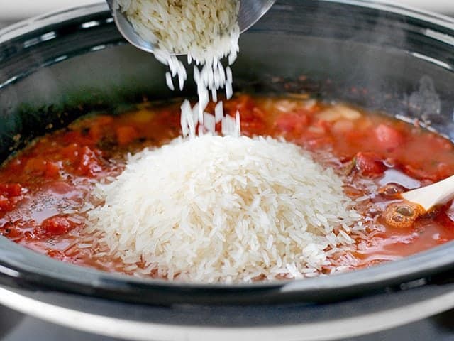 Rice being poured into slow cooker 