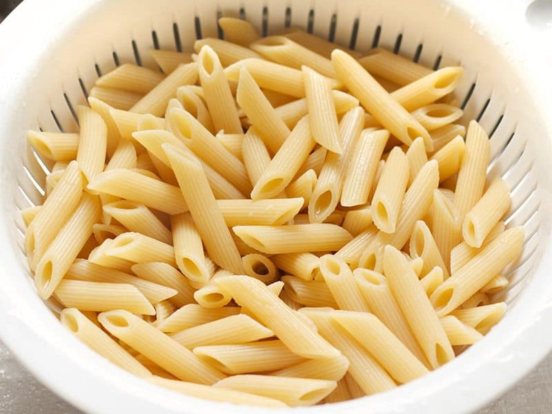 Cooked penne pasta in a colander