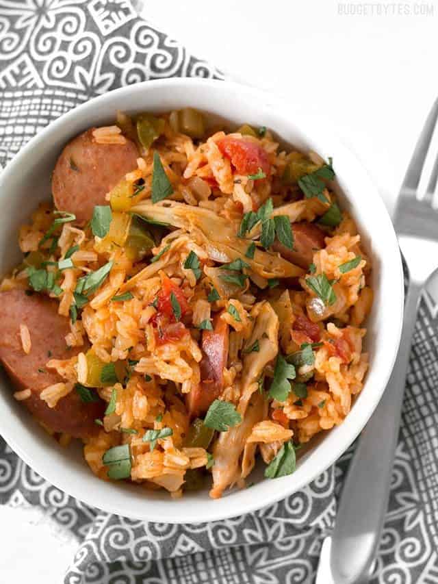 Top view of a bowl of Slow Cooker Jambalaya sitting on a patterned napkin with a fork on the side 